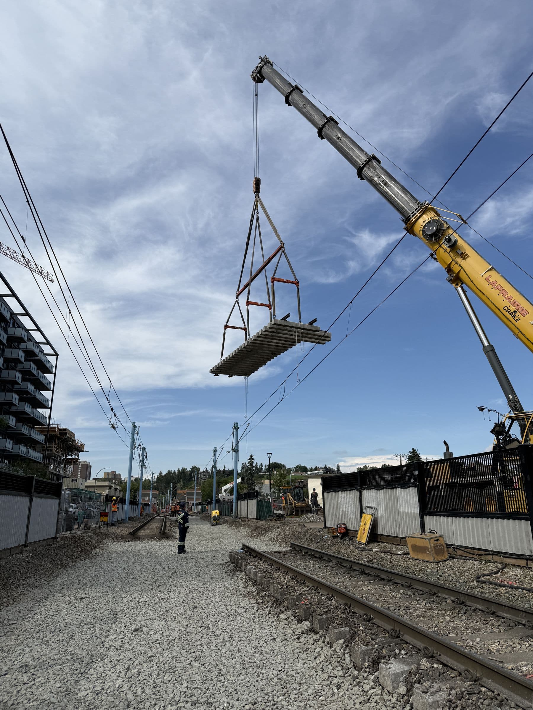 Crane lifting a track panel over a Calgary LRT crossover work site