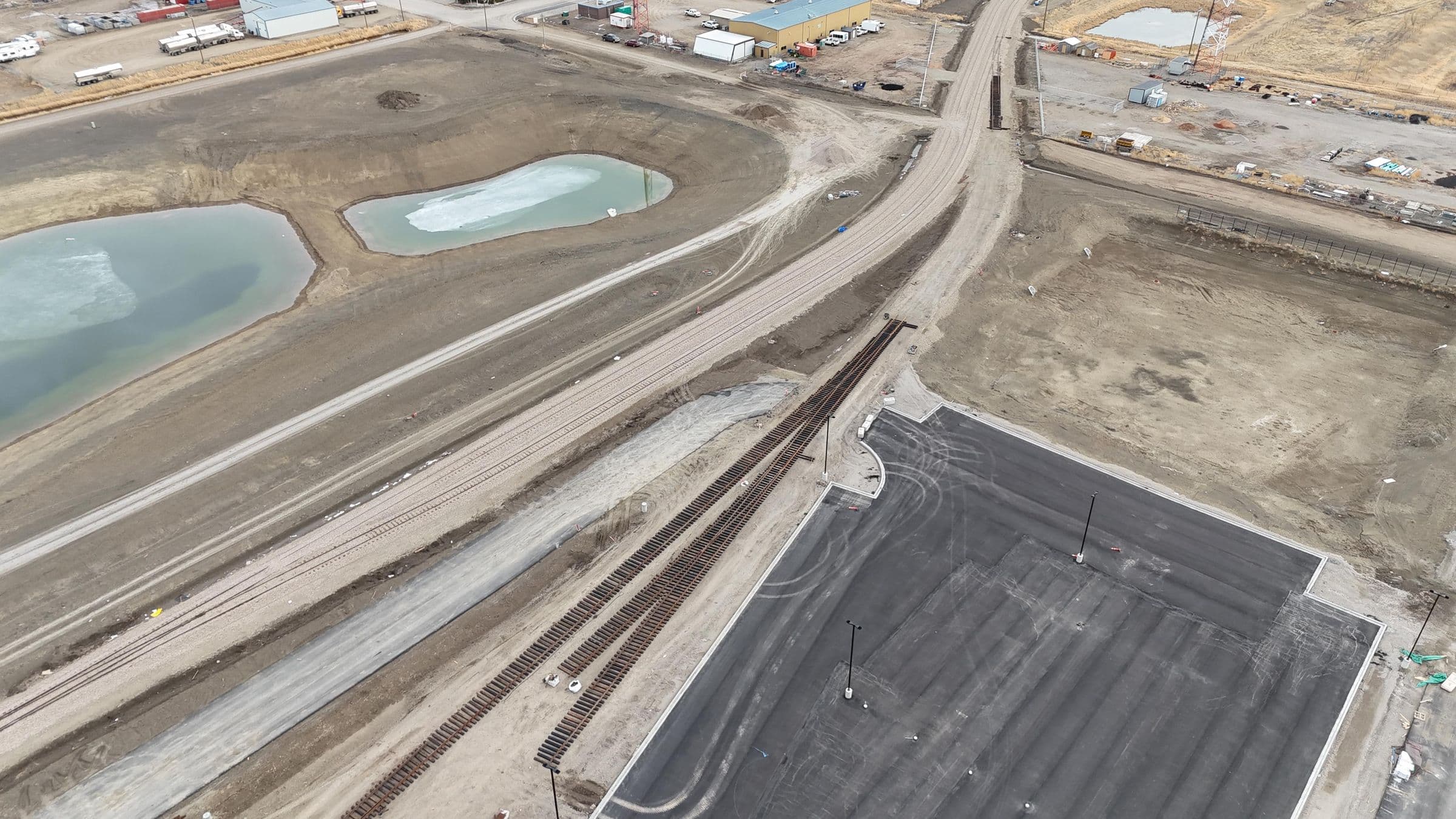 Aerial view of new railway track running beside a paved facility lot