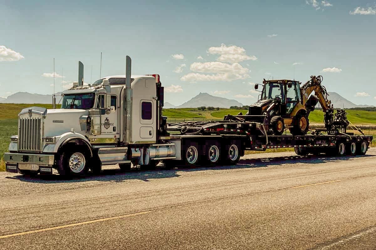 Kenworth tractor hauling railway equipment on a lowboy